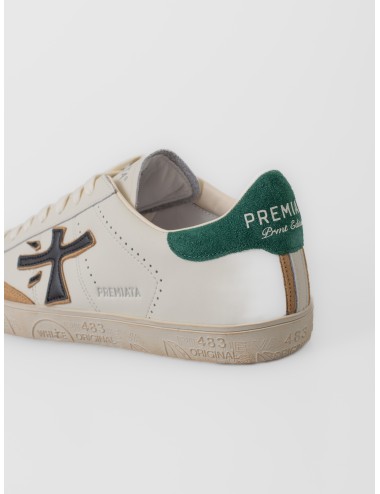 Zapatilla blanco roto Premiata Steven 7284 con logo negro, talón verde y suela gráfica