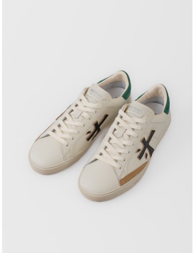 Zapatilla blanco roto Premiata Steven 7284 con logo negro, talón verde y suela gráfica