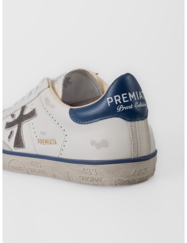 Zapatilla blanca Premiata Steven 7503 con logo lateral oscuro, talón azul y suela gráfica